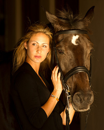 Rider poses with here horse at stables