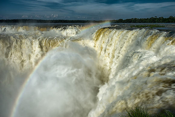Looking into 'Devil's Throat' from the top of Iguazu Falls with half a rainbow from the Argentina side .653